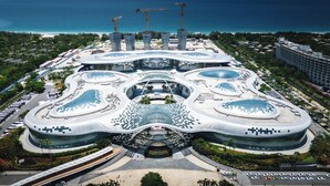 Un edifici modern d'arquitectura amb un atrium central, envoltat d'espais verds i vista al mar.