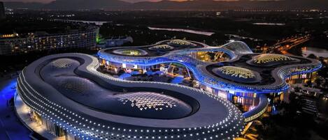 A modern, circular building with a unique architectural design, surrounded by a well-lit area.