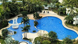 Una gran piscina amb diverses línies, envoltada de palmeres i un jardí paisatjista.