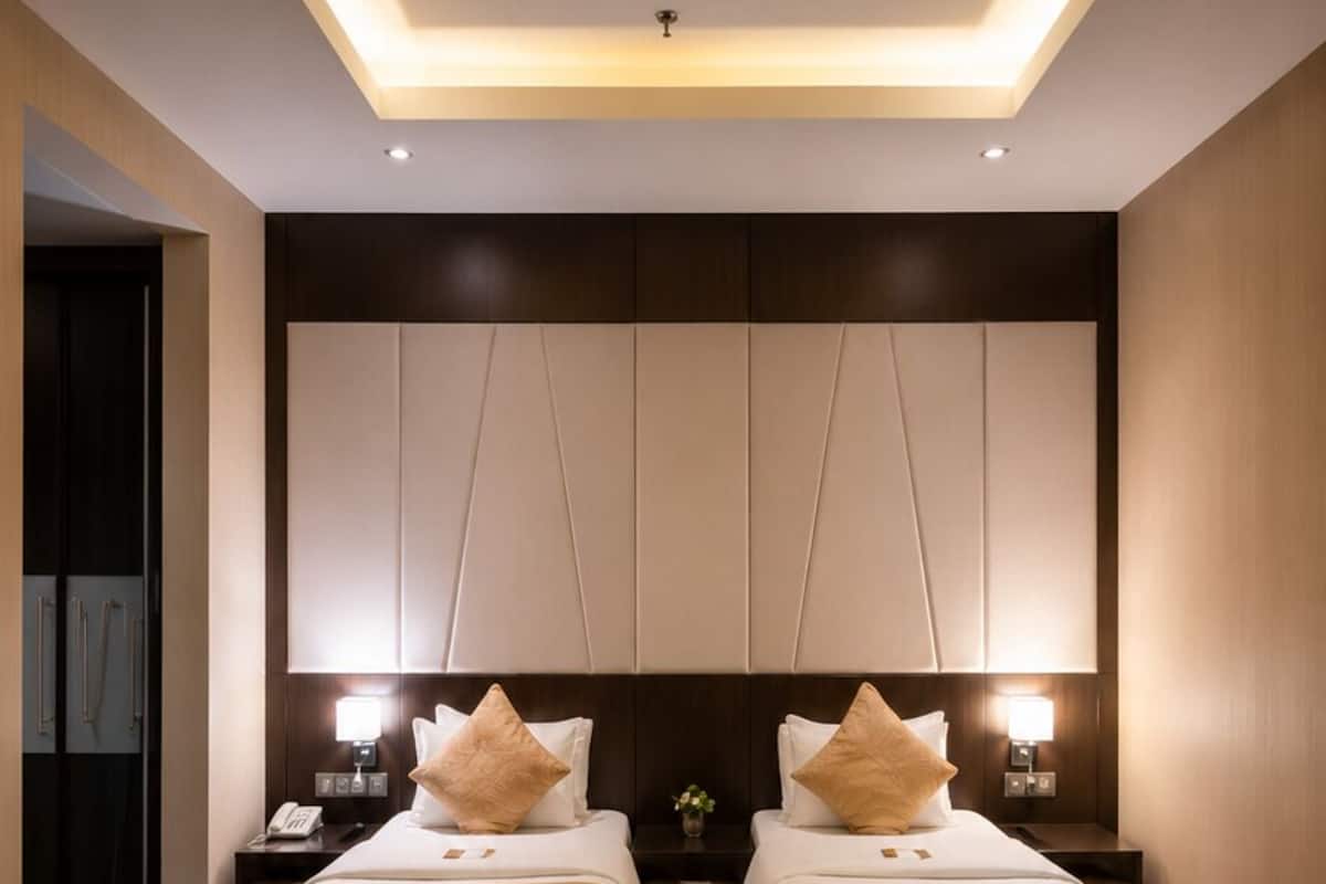 A hotel room with two beds, a large wall unit, and a patterned carpet.