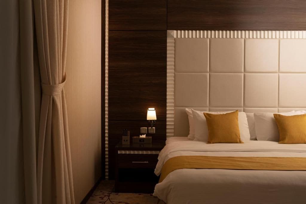 A hotel room with a large bed, a nightstand with a lamp, and a wooden headboard.