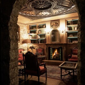 A cozy interior with a fireplace, bookshelves, and a stone archway. - Kamares Boutique Hotel & Spa Ioannina (Ioannina)