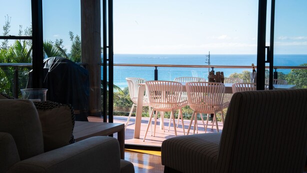 Een balkon met uitzicht op de oceaan, een tafel met stoelen en een bank.