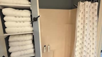 Ein Duschbereich mit Duschvorhang, Handtuchhalter und gefalteten Handtüchern sowie einer Duschbrause.