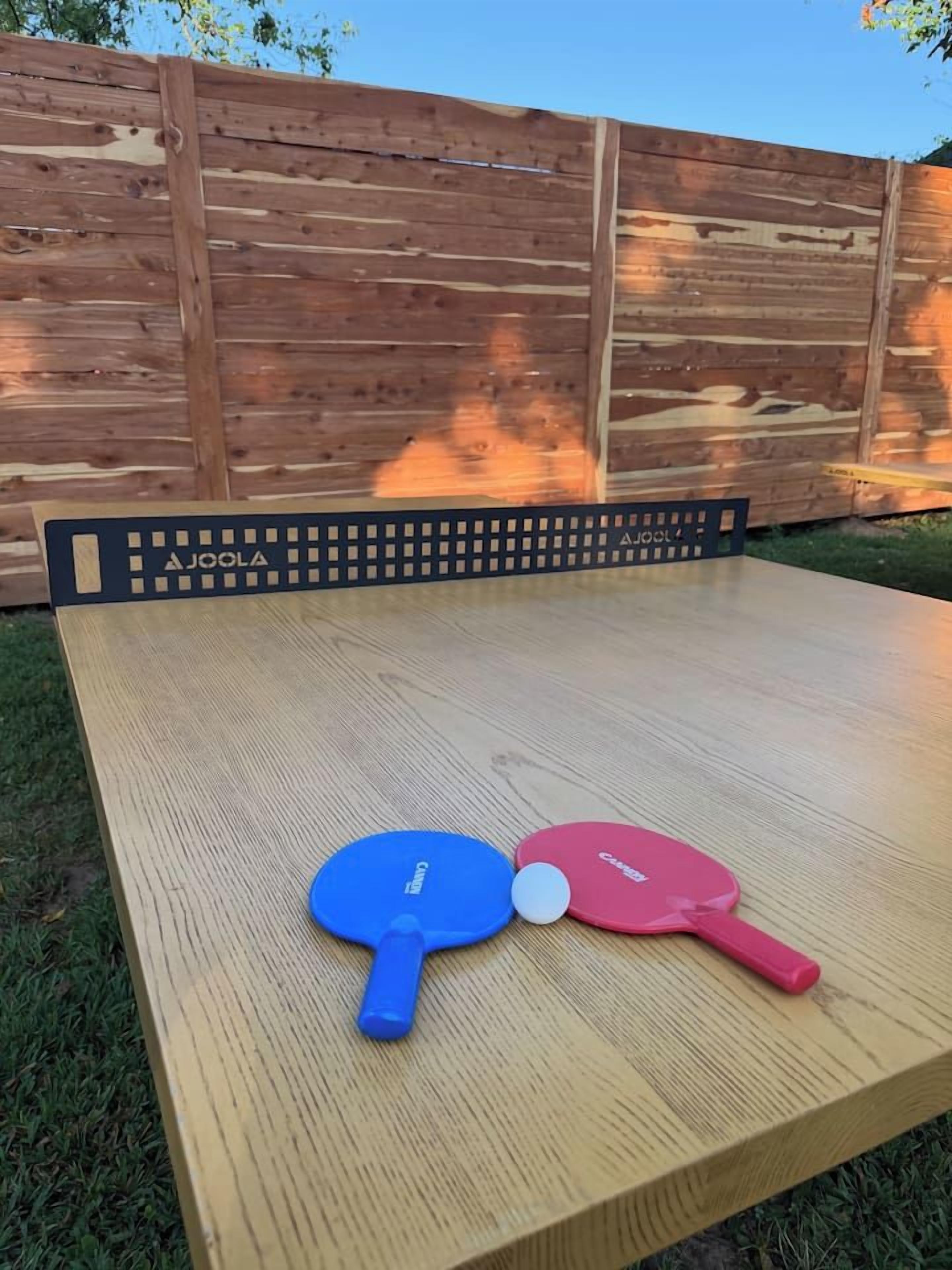 Ein Holztisch mit zwei Tischtennis Schlägern und einem Ball.