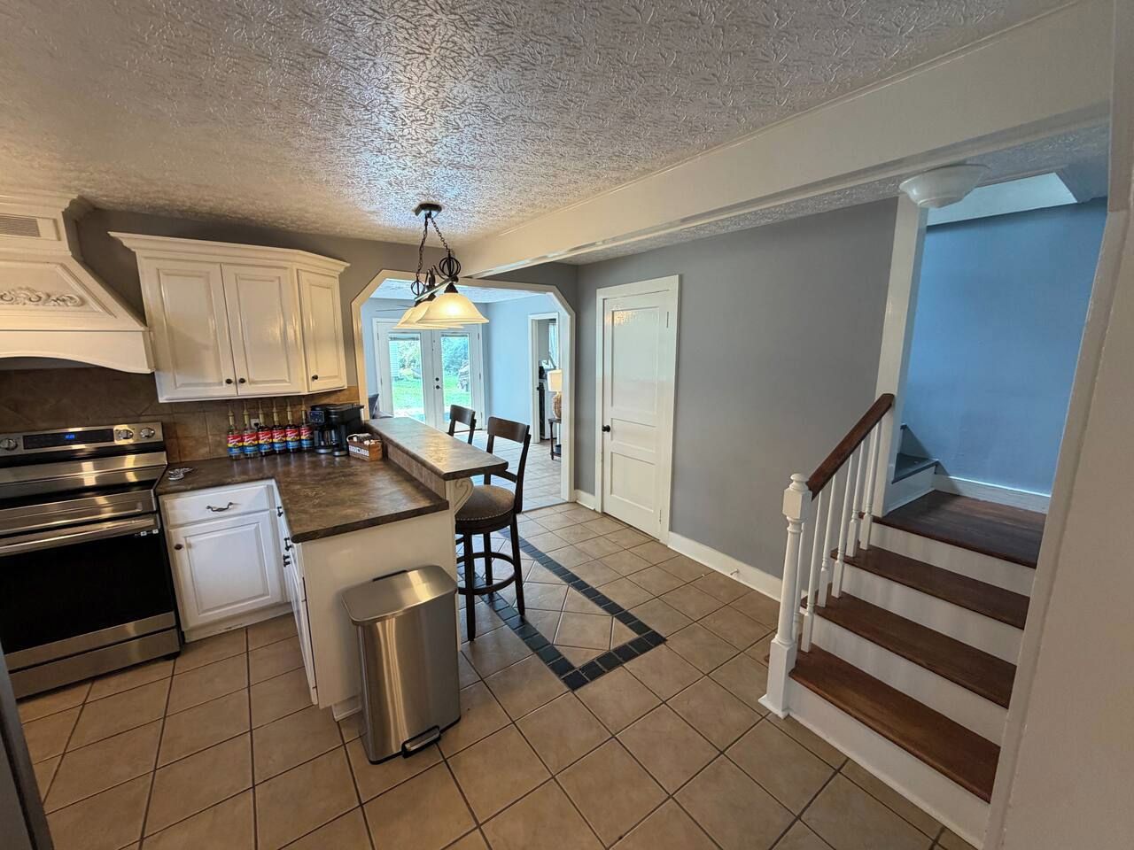 A kitchen with a central island, built-in oven, and stainless steel appliances.