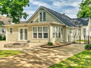 A single-story house with a front porch, a stone fire pit, and a well-maintained lawn. - Spacious home with in ground pool in Russellville (Russellville)