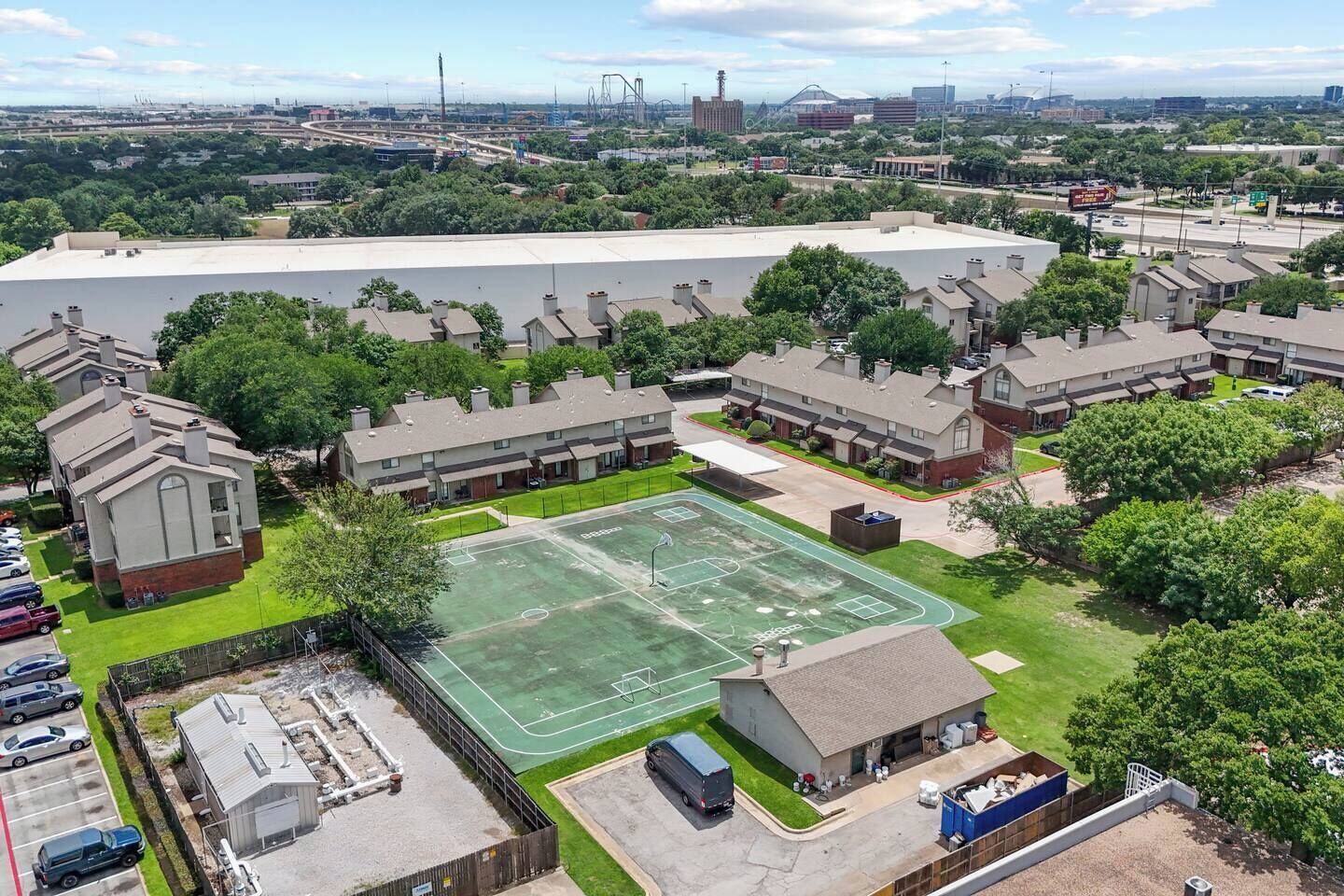 A residential area with a large building, a basketball court, and several houses.