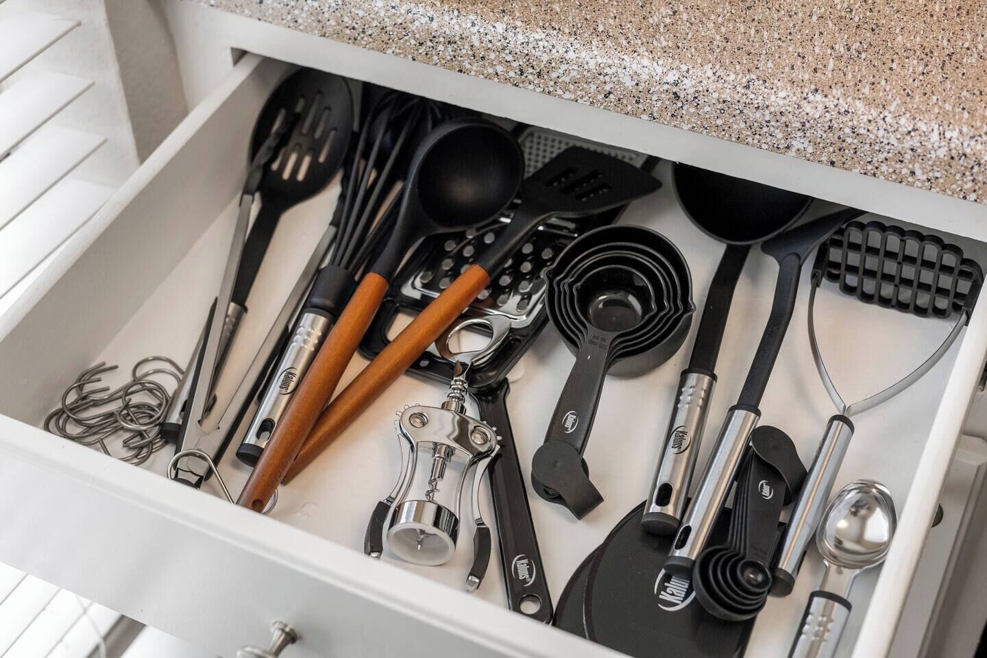 A drawer containing various kitchen utensils including spatulas, spoons, and a can opener.