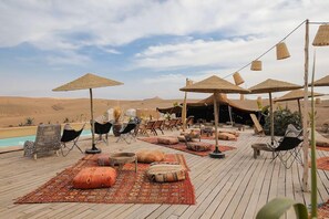 A desert resort with outdoor seating, umbrellas, and a pool. - Mia Agafay Resort (Agafay)
