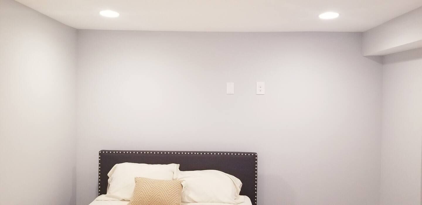 A bedroom with a bed, white walls, and a ceiling light.