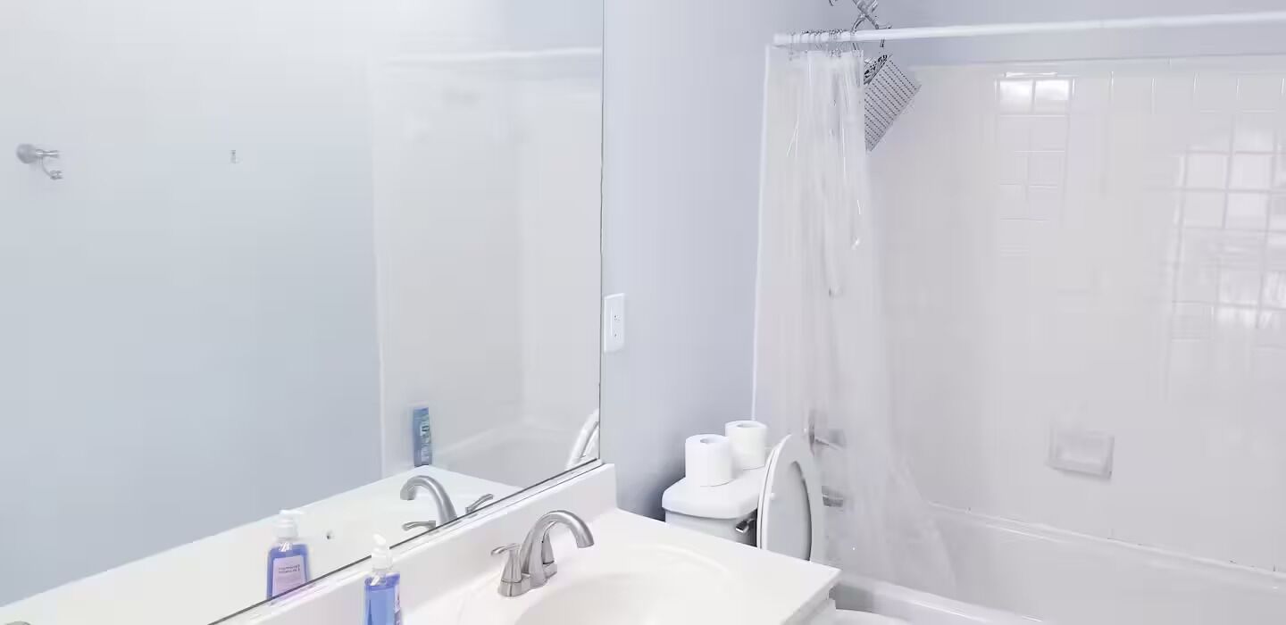 A bathroom with a white sink, mirror, and shower curtain.