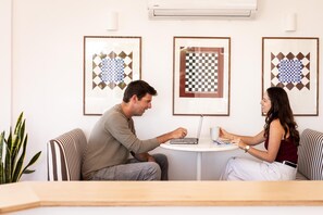 A room with a round table, two framed artworks, a potted plant, and a wall-mounted air conditioner. - Outsite Vilamoura Adults Only (Loulé)