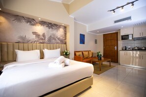 A hotel room with a bed, a sofa, a dining table, a kitchen area, and a wall with a leaf pattern. - Vibotel Residence (New Cairo)