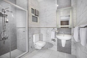 A modern bathroom with a glass shower enclosure, a toilet, a sink, and a mirror. - Vibotel Residence (New Cairo)