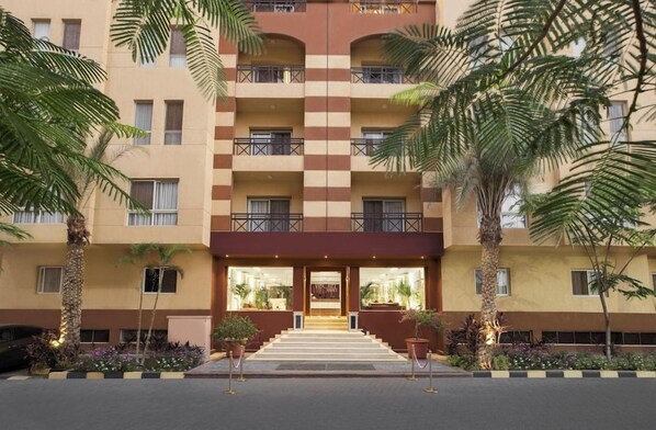 A multi-story hotel with a checkered facade, balconies, and a central entrance with steps. - Vibotel Residence (New Cairo)
