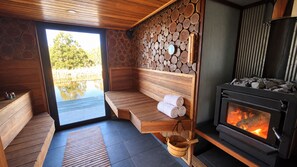 Uma sala de sauna com um banco de madeira, uma parede de pedra e um fogão a lenha.