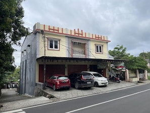 A two-story building with a flat roof, a covered entrance, and a signboard.