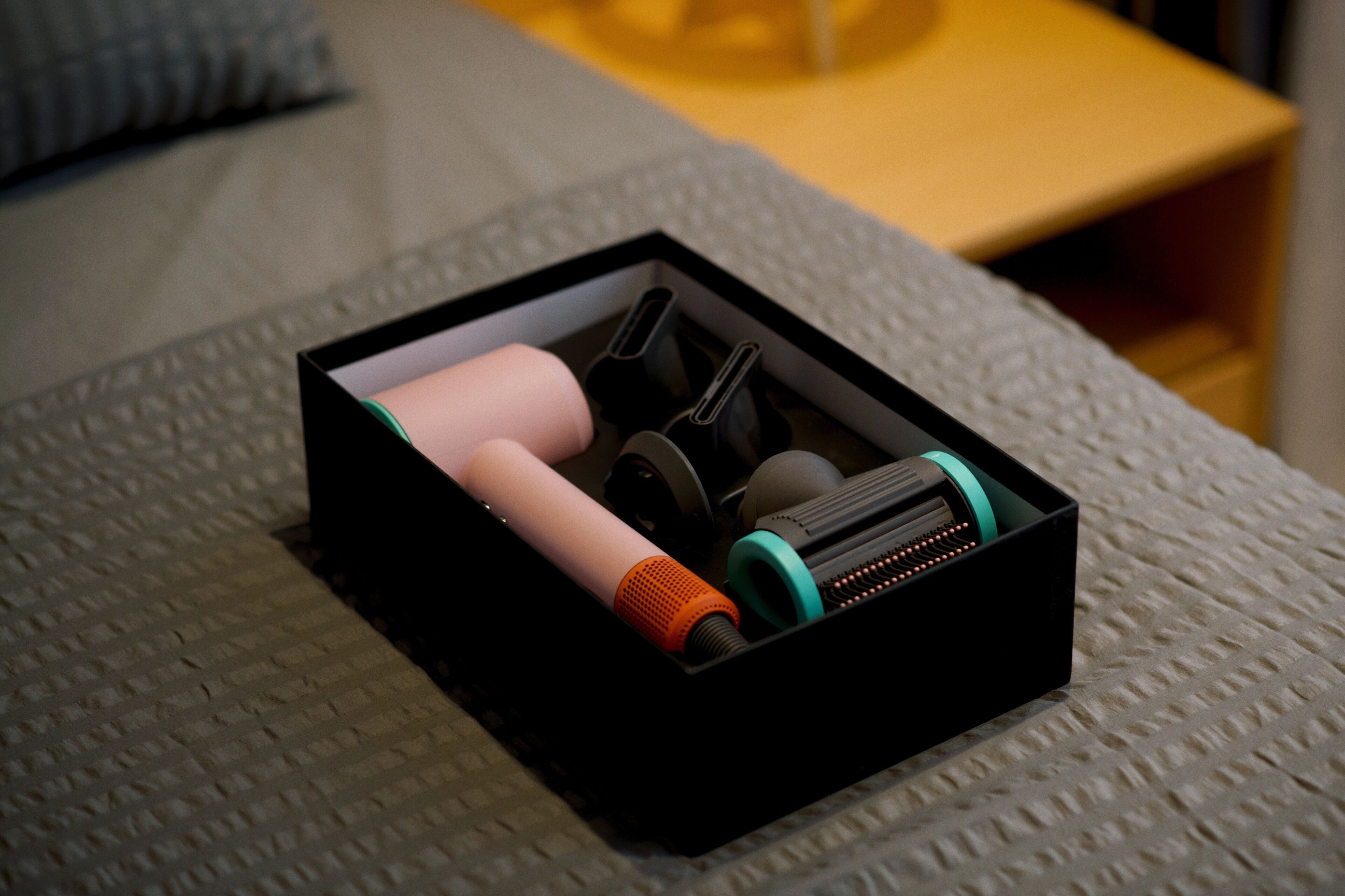 A black box with cylindrical objects and a small orange item on a textured surface.