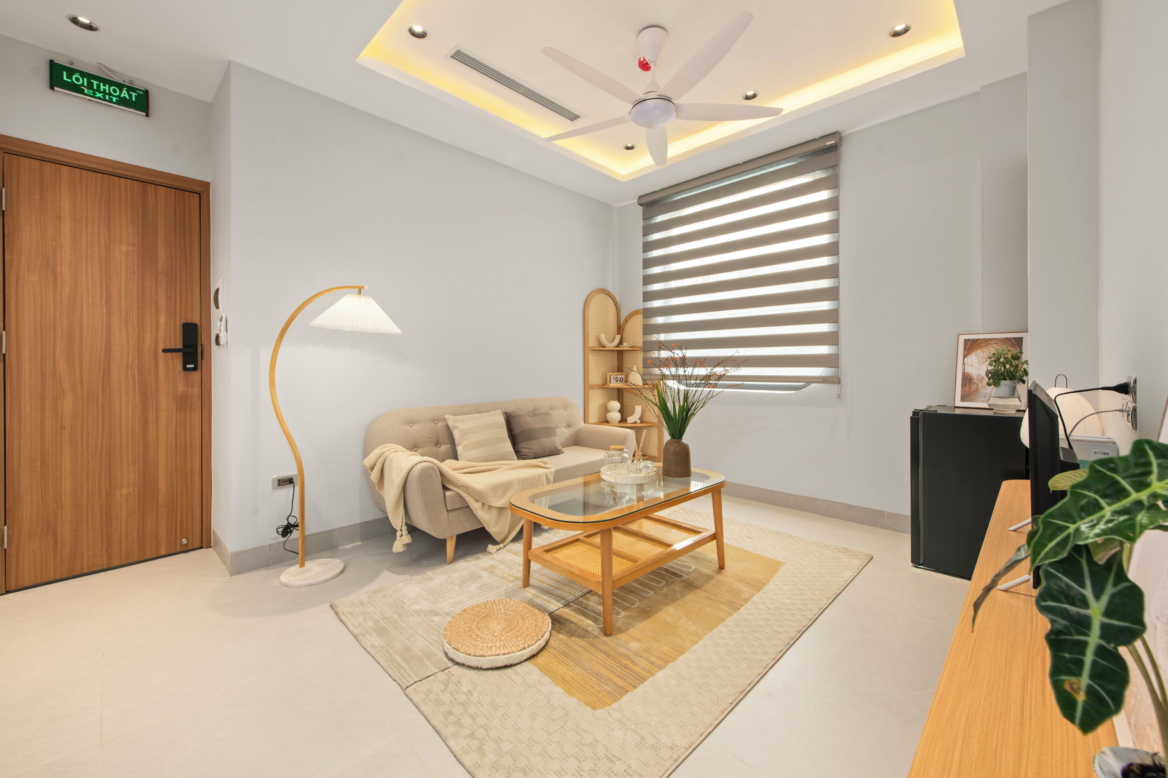 Un salon moderne avec un canapé, une table basse, une lampe et un ventilateur de plafond.