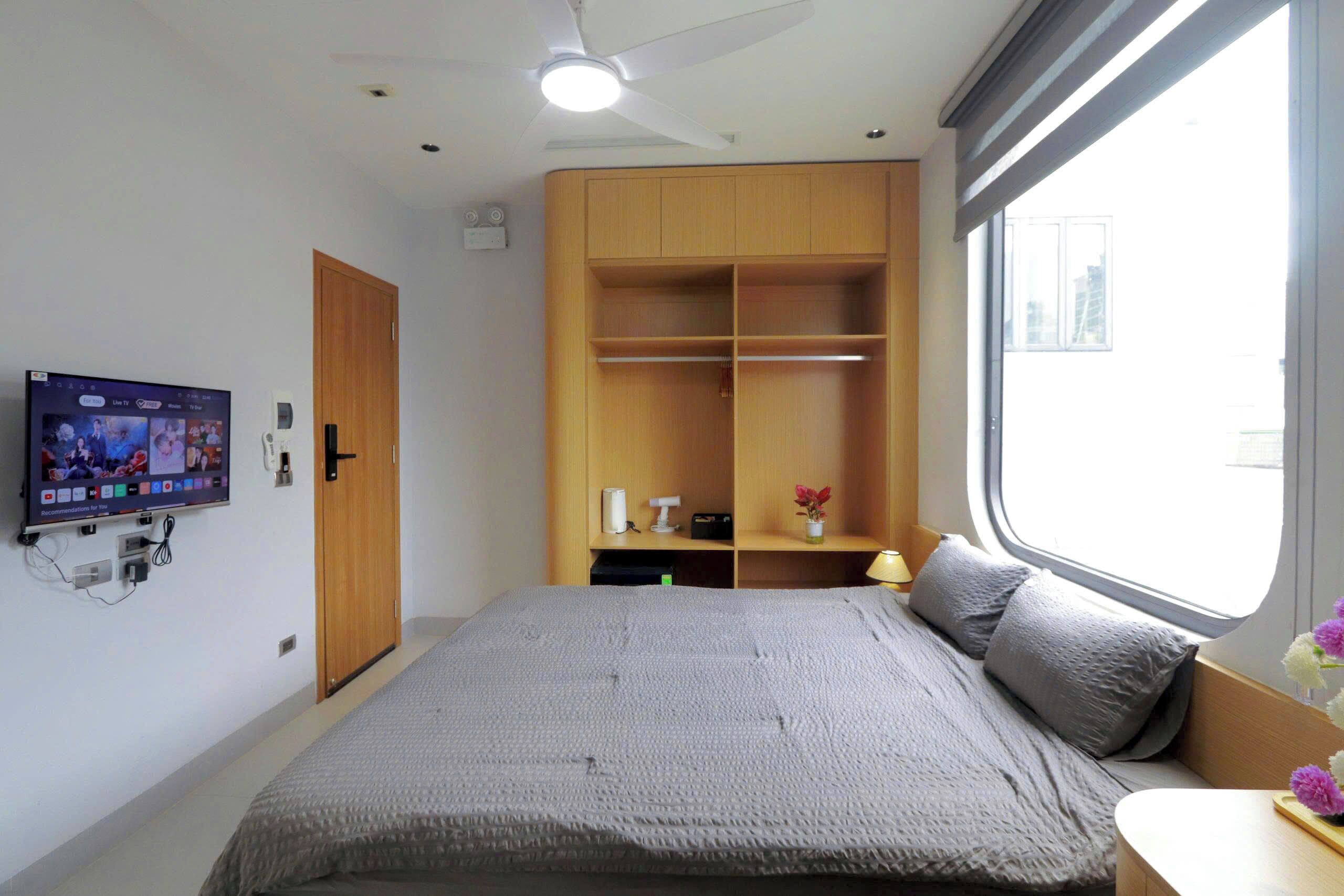 Een slaapkamer met een bed, een televisie, een kledingkast en een raam.