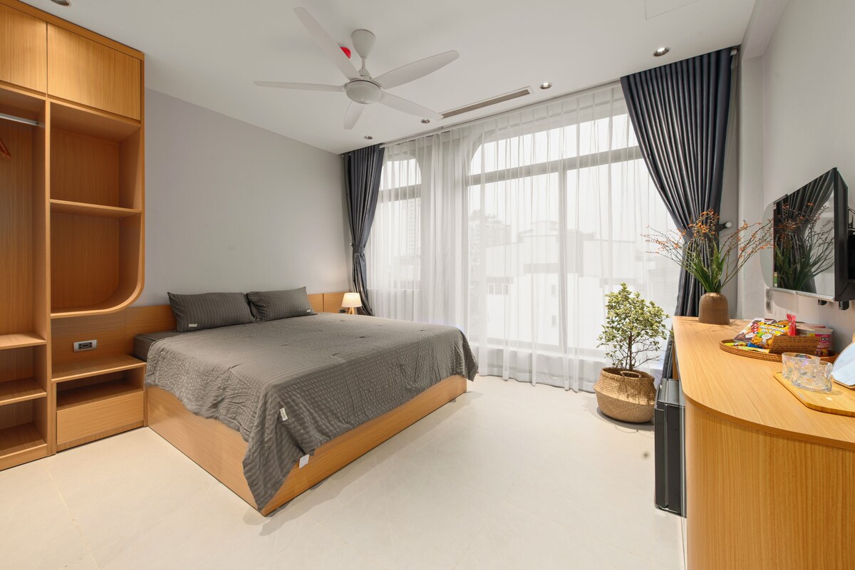 A modern bedroom with a bed, built-in wardrobe, bedside table, and a small desk area.