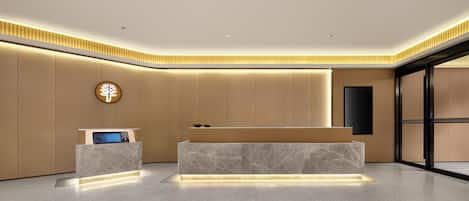 A modern reception area with a marble reception desk, a digital display, and a wall-mounted clock.