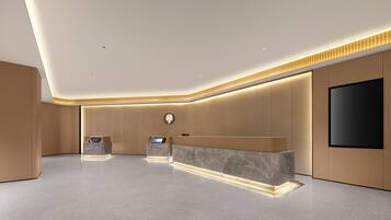 A modern reception area with a marble reception desk, a digital display, and a flat-screen TV mounted on the wall.