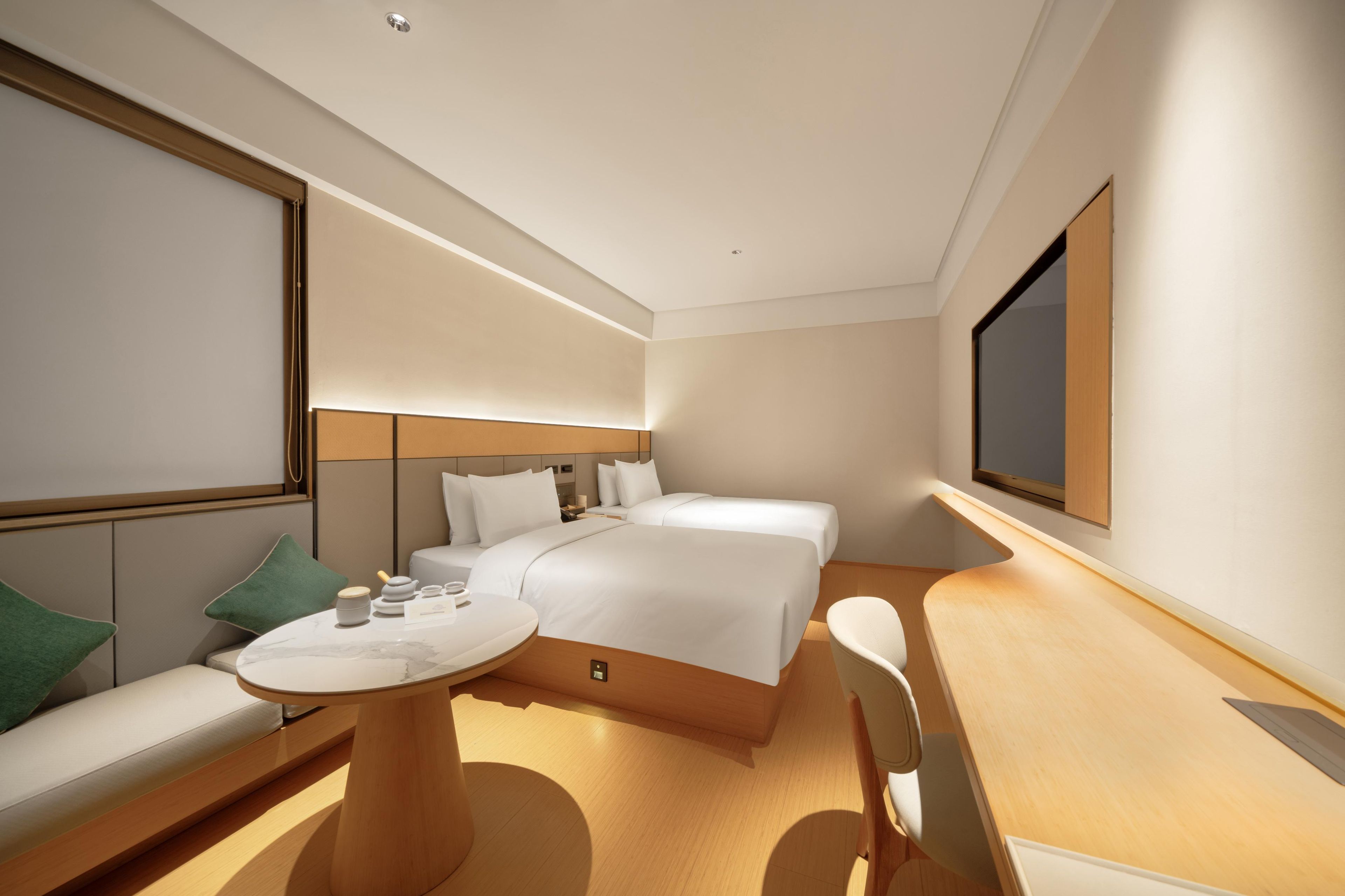 A modern hotel room with a large bed, a seating area with a table, and a television mounted on the wall.