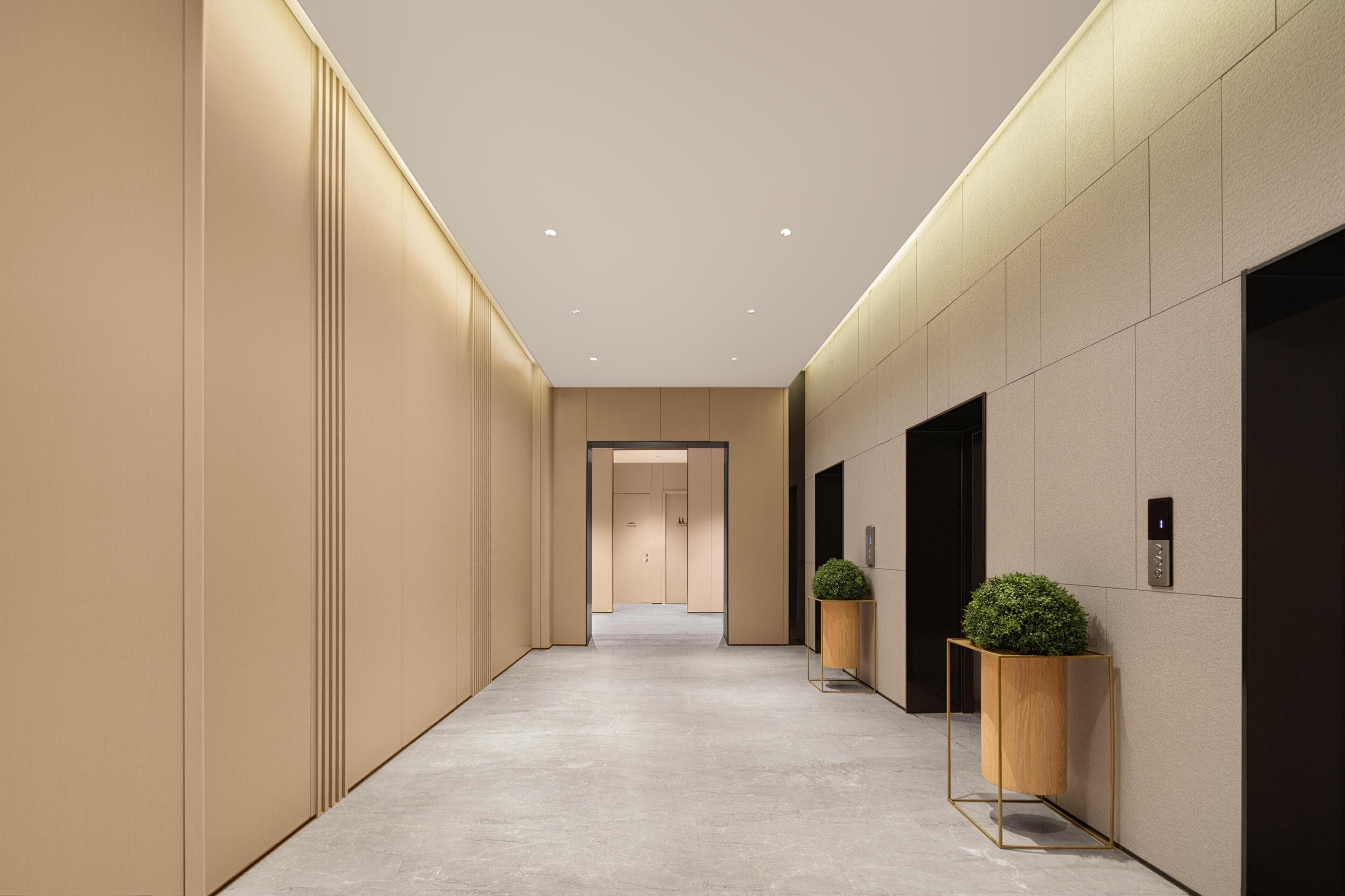 A modern hallway with a light-colored floor, beige walls, and recessed ceiling lights.