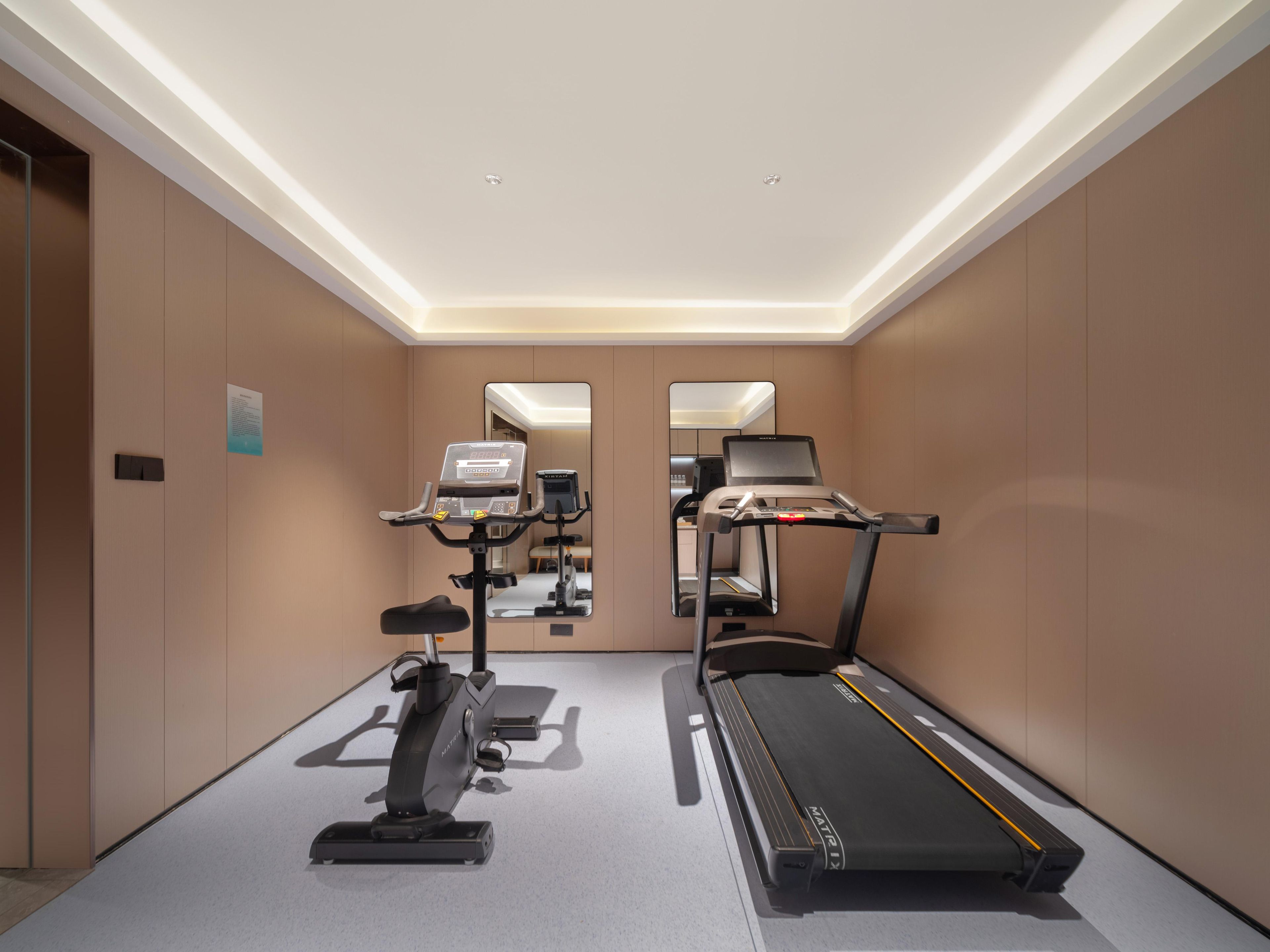 A gym with a treadmill, stationary bike, and elliptical machine.