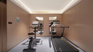 A gym with a treadmill, stationary bike, and elliptical machine.