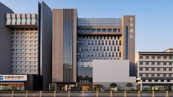 A modern hotel with a prominent entrance, multiple floors, and a clear sky.