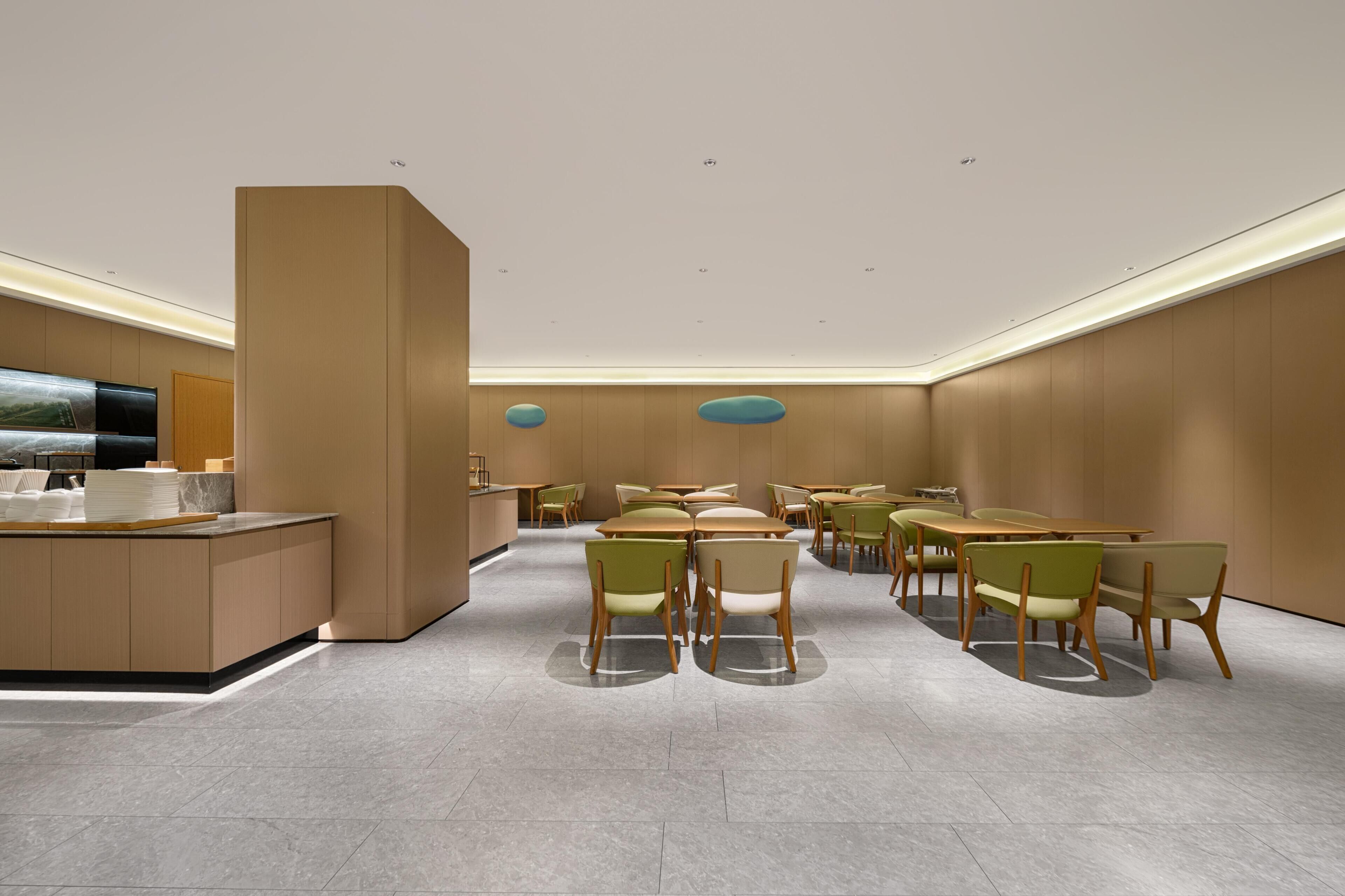 A modern hotel lobby with a reception desk, seating area, and a large flat-screen TV.