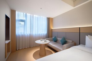 Ein modernes Hotelzimmer mit großem Fenster, einem runden Tisch, einer Couch und einem Bett.