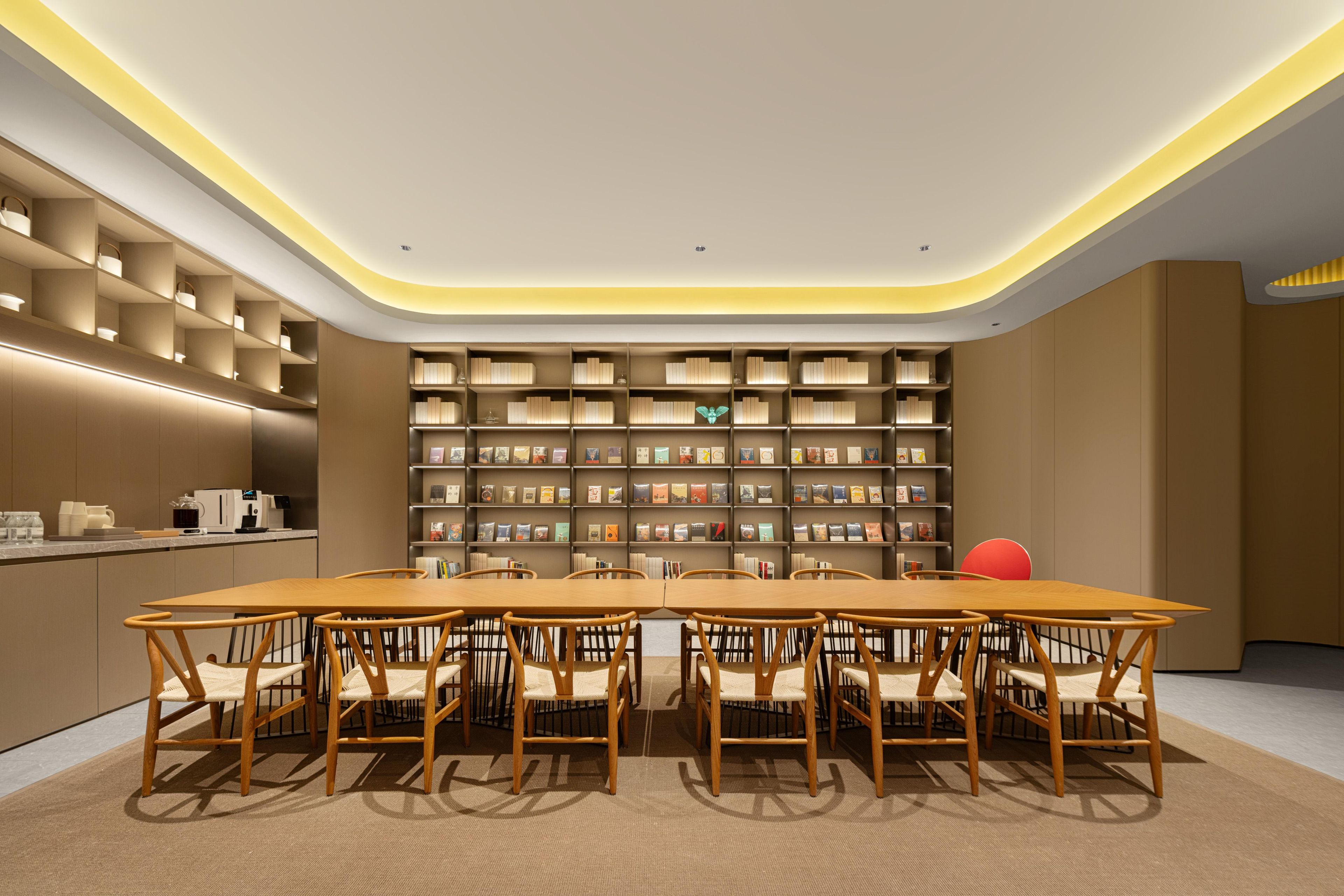 Una biblioteca moderna con una mesa central y sillas, rodeada de estanterías.
