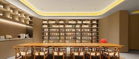 Una biblioteca moderna con una mesa central y sillas, rodeada de estanterías.