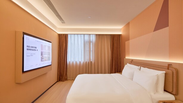 Una habitación de hotel con una cama, un televisor en la pared y una ventana con cortinas.