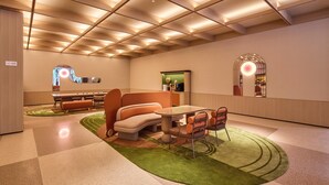 Un interior moderno con piso a cuadros, un área de estar central con mesa y sillas, y una ventana de arco distintivo.