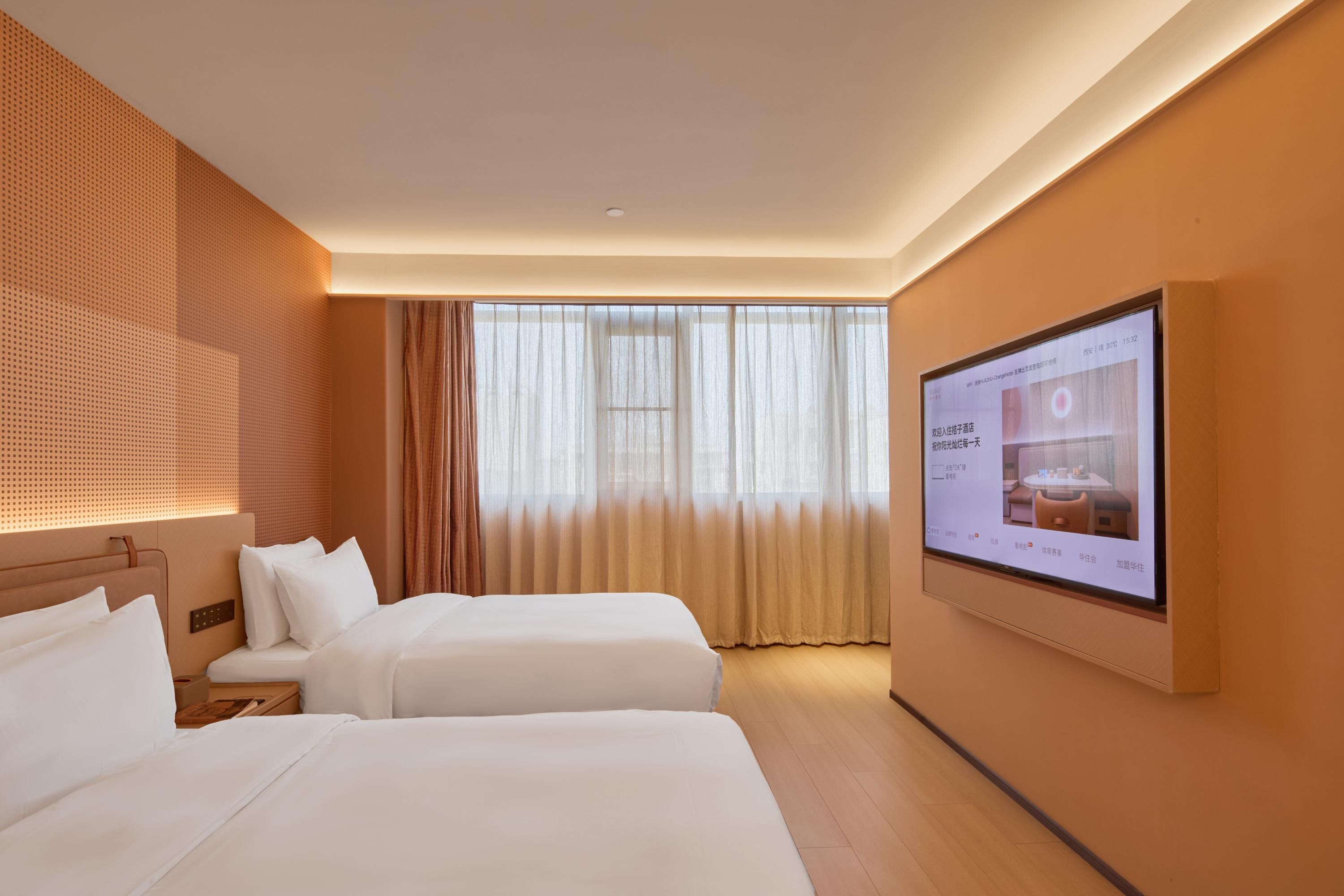 Ein Hotelzimmer mit zwei Betten, einem großen Fenster mit durchsichtigen Vorhängen, einem an der Wand befestigten Fernseher und einem Holzboden.