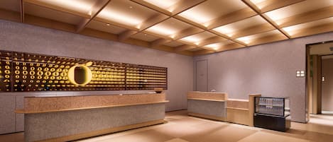 Una zona de recepción con diseño moderno, que incluye un mostrador grande, una pared con motivos circulares e iluminación empotrada en el techo.