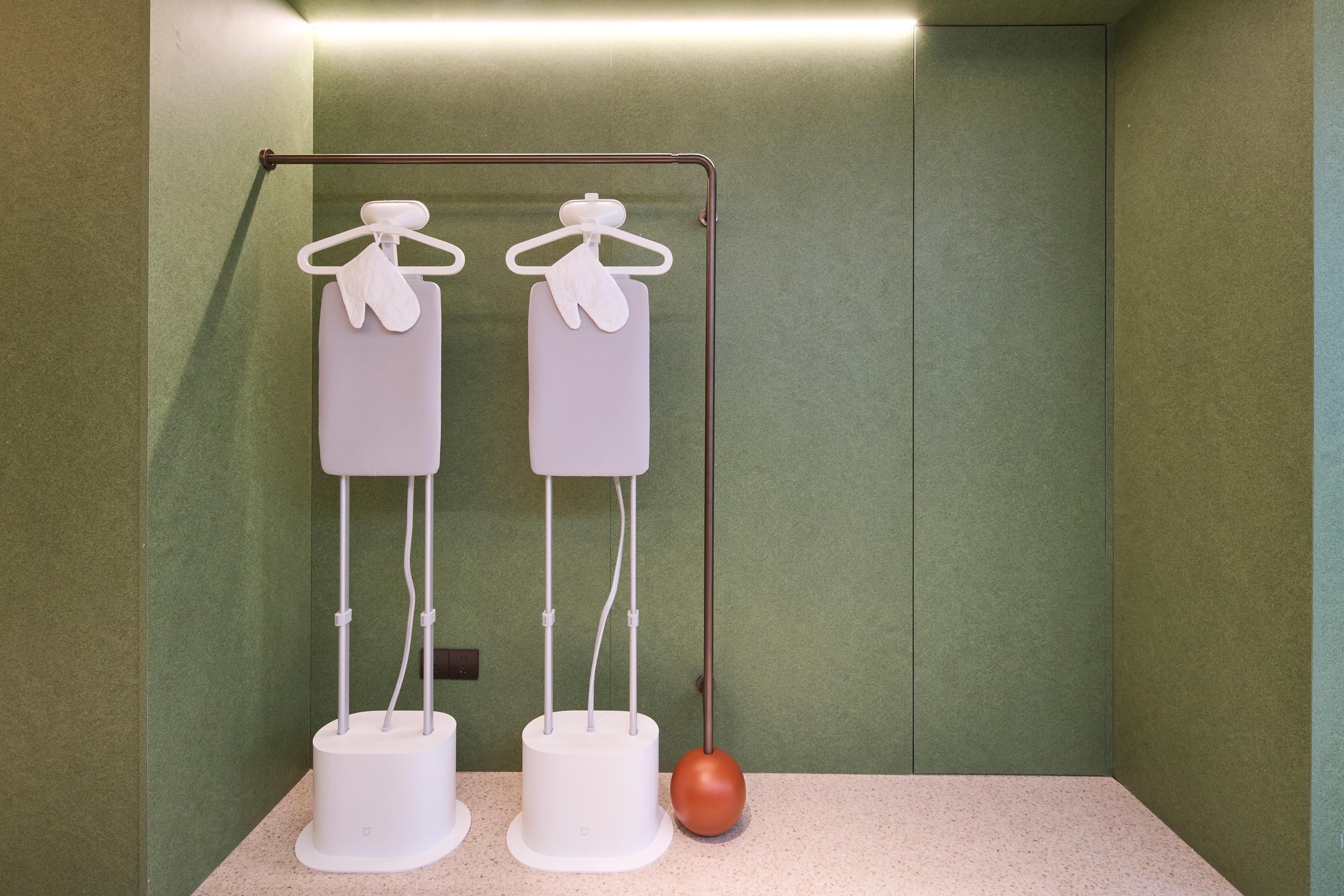 A room with two white cylindrical objects on stands, a metal rack with two white items, and a single orange spherical object on the floor.