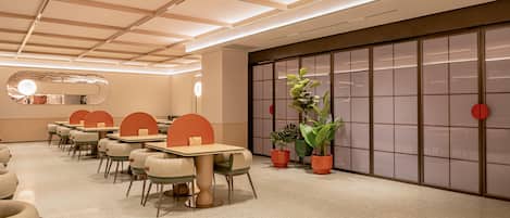 A conference room with tables and chairs, a large sliding door, and a plant.