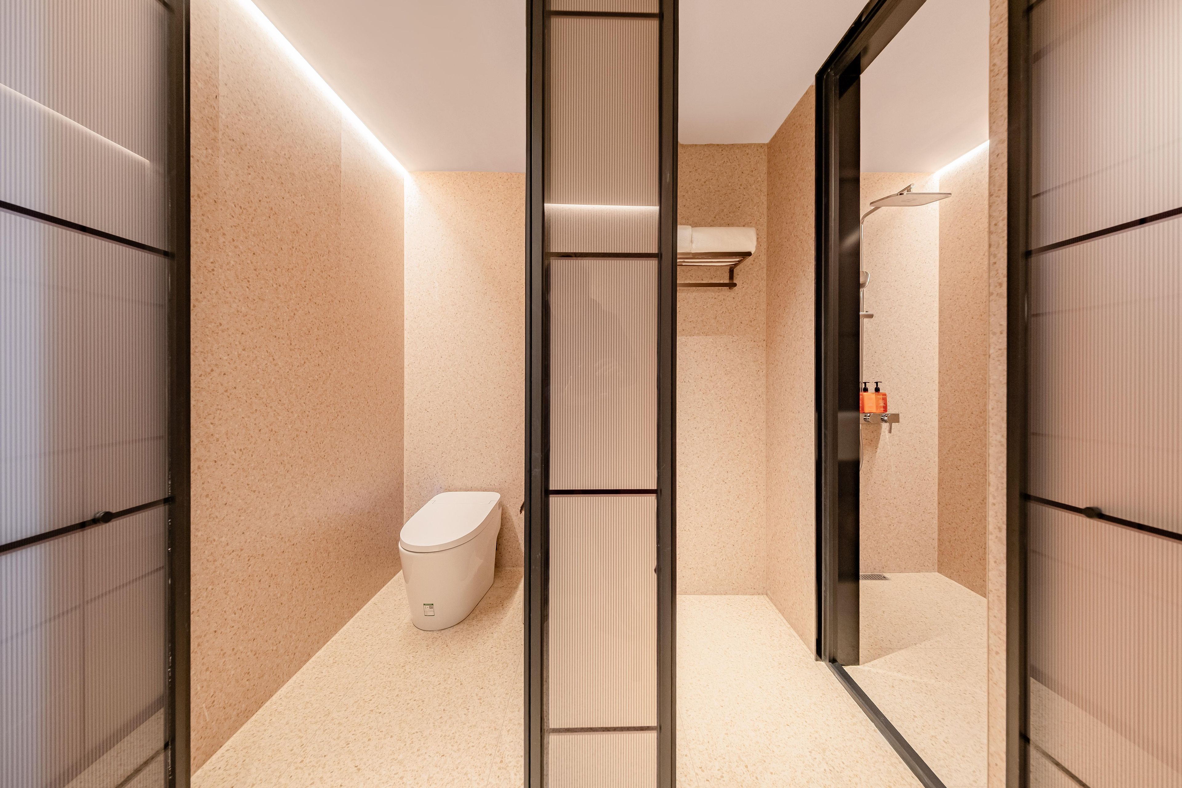 Une salle de bain moderne équipée de toilettes, d’un porte-serviettes et d’un espace douche.