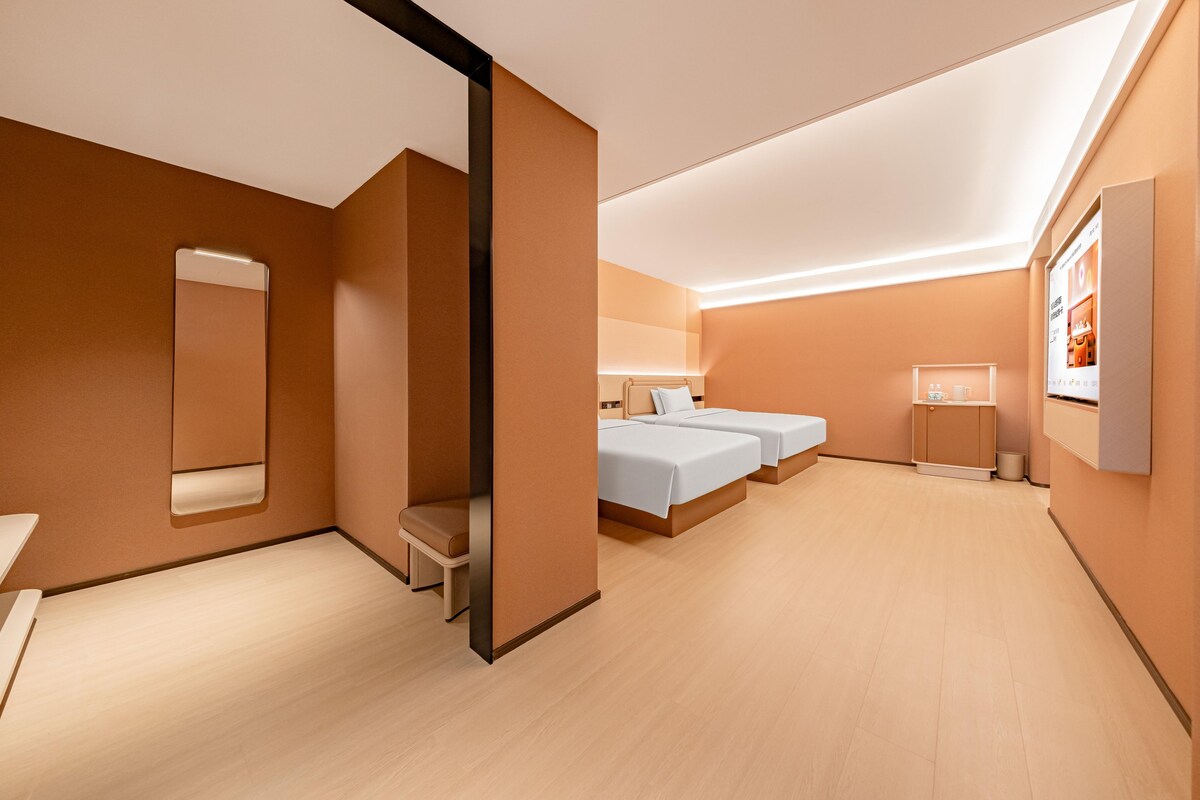 Ein modernes Hotelzimmer mit einem großen Bett, einem Einzelbett, einer Sitzecke, einem Spiegel und einem Badezimmer.