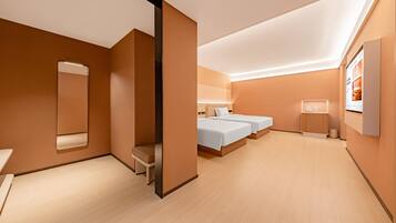 Habitación de hotel moderna con una cama grande, una cama más pequeña, un área de descanso, un espejo y un baño.