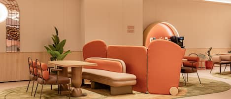 A modern lounge area with a sofa, chairs, a table, and a coffee machine.