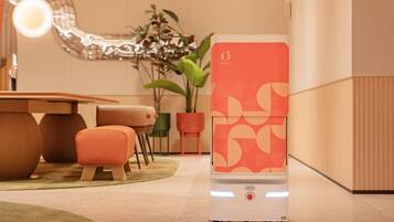 A modern room with a standing heater, a dining table, chairs, and a potted plant.
