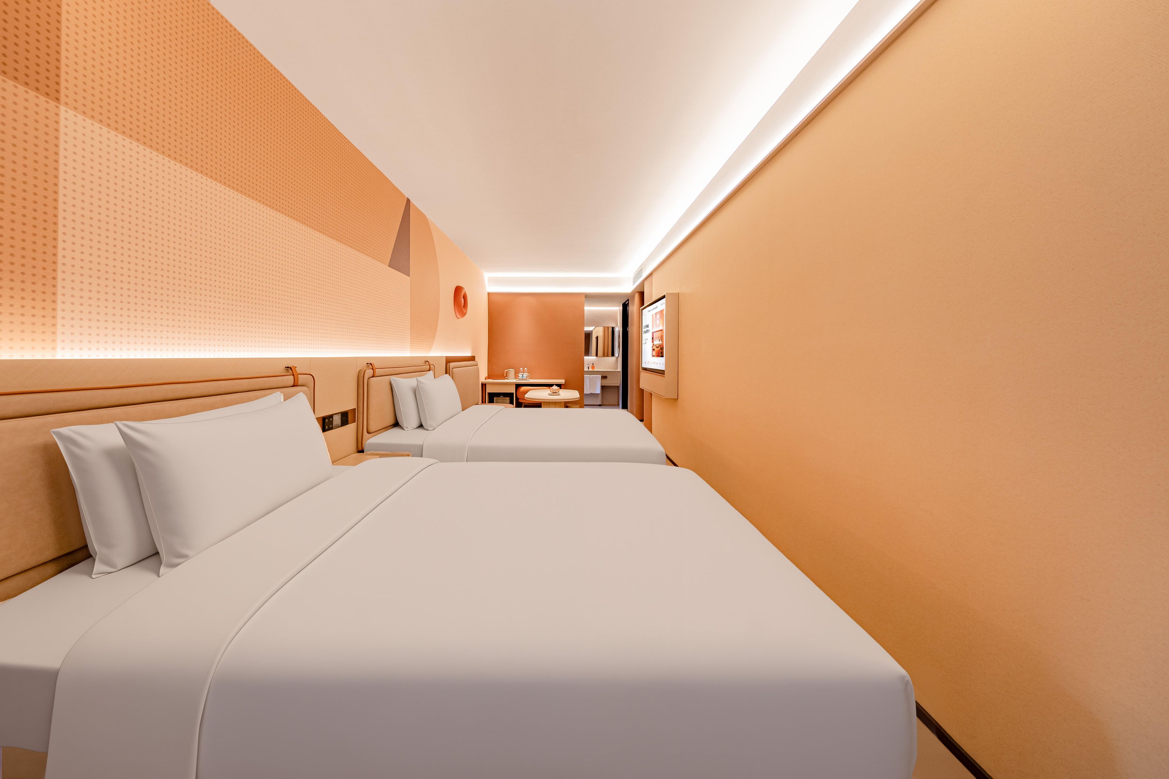 Ein Hotelzimmer mit zwei Betten, einem kleinen Tisch und einem Spiegel.