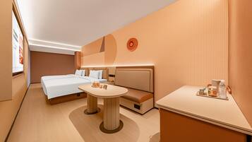 A hotel room with a bed, a sofa, a small table, and a wall-mounted light fixture.